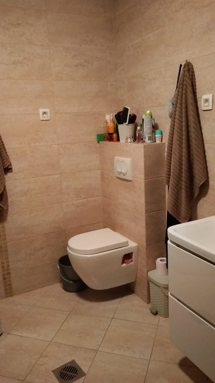 Savremeno kupatilo sa visećom WC šoljom i bež pločicama u stanu u Budvi, Crna Gora.