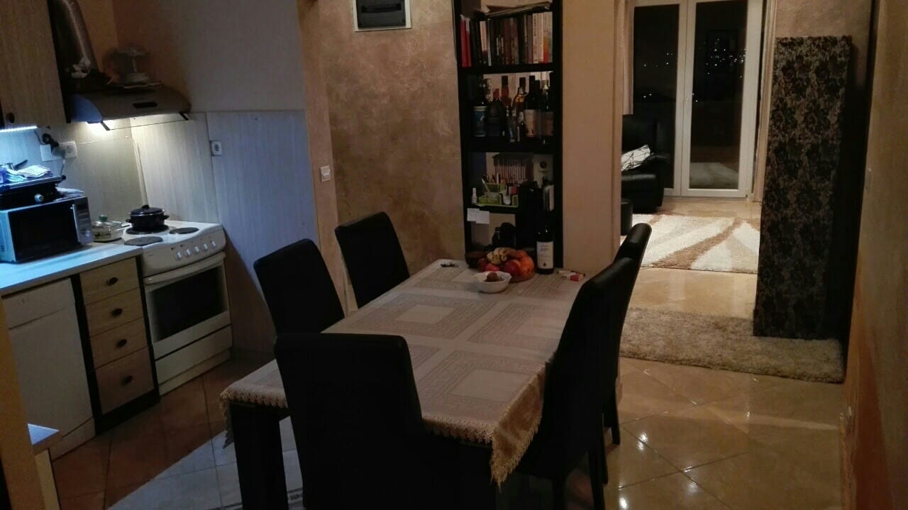 Enterijer kuhinje-trpezarije u stanu u Kotoru, Crna Gora: trpezarijski sto, kuhinjski elementi i izlaz na terasu.
