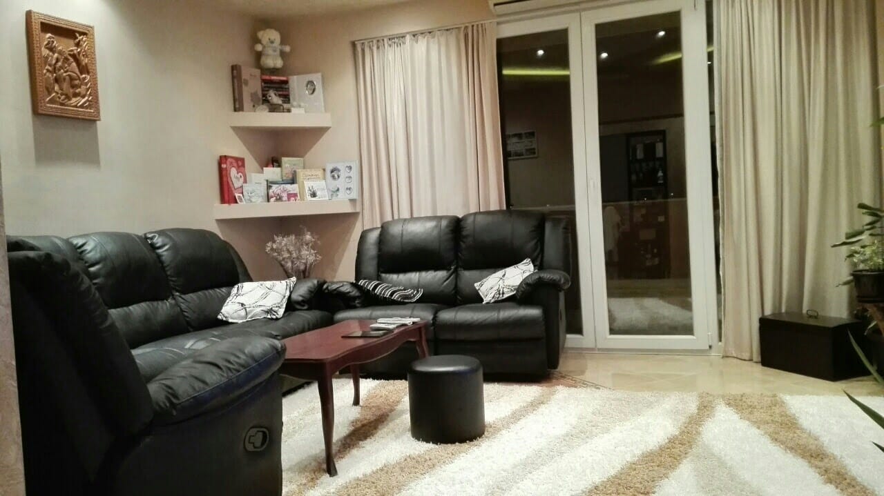Ugodan dnevni boravak sa crnim kožnim sofama i panoramskim izlazom na terasu u stanu, Kotor, Crna Gora.