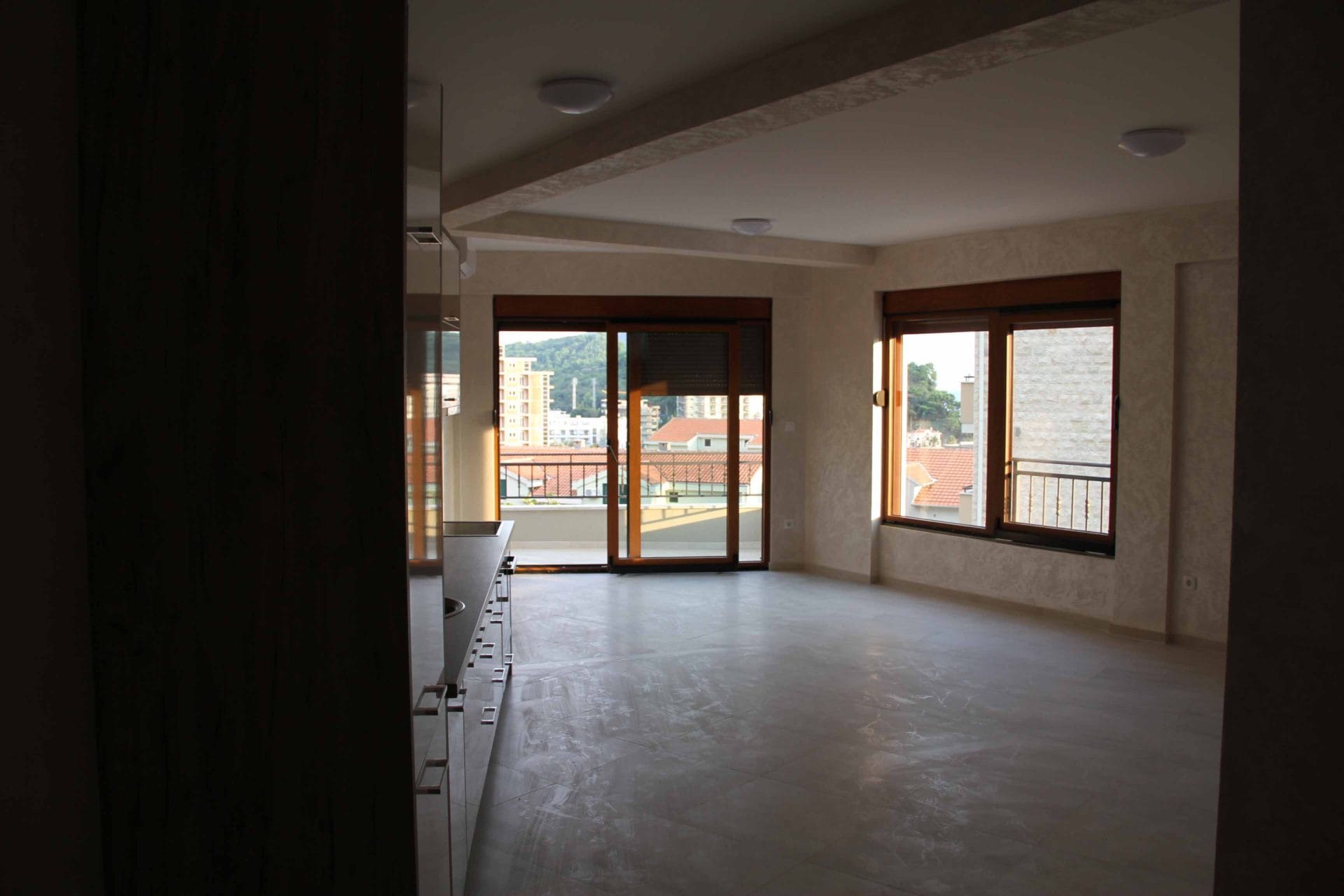 Bright living room with kitchen and access to the terrace in an apartment, Petrovac, Montenegro. Panoramic windows and city view.