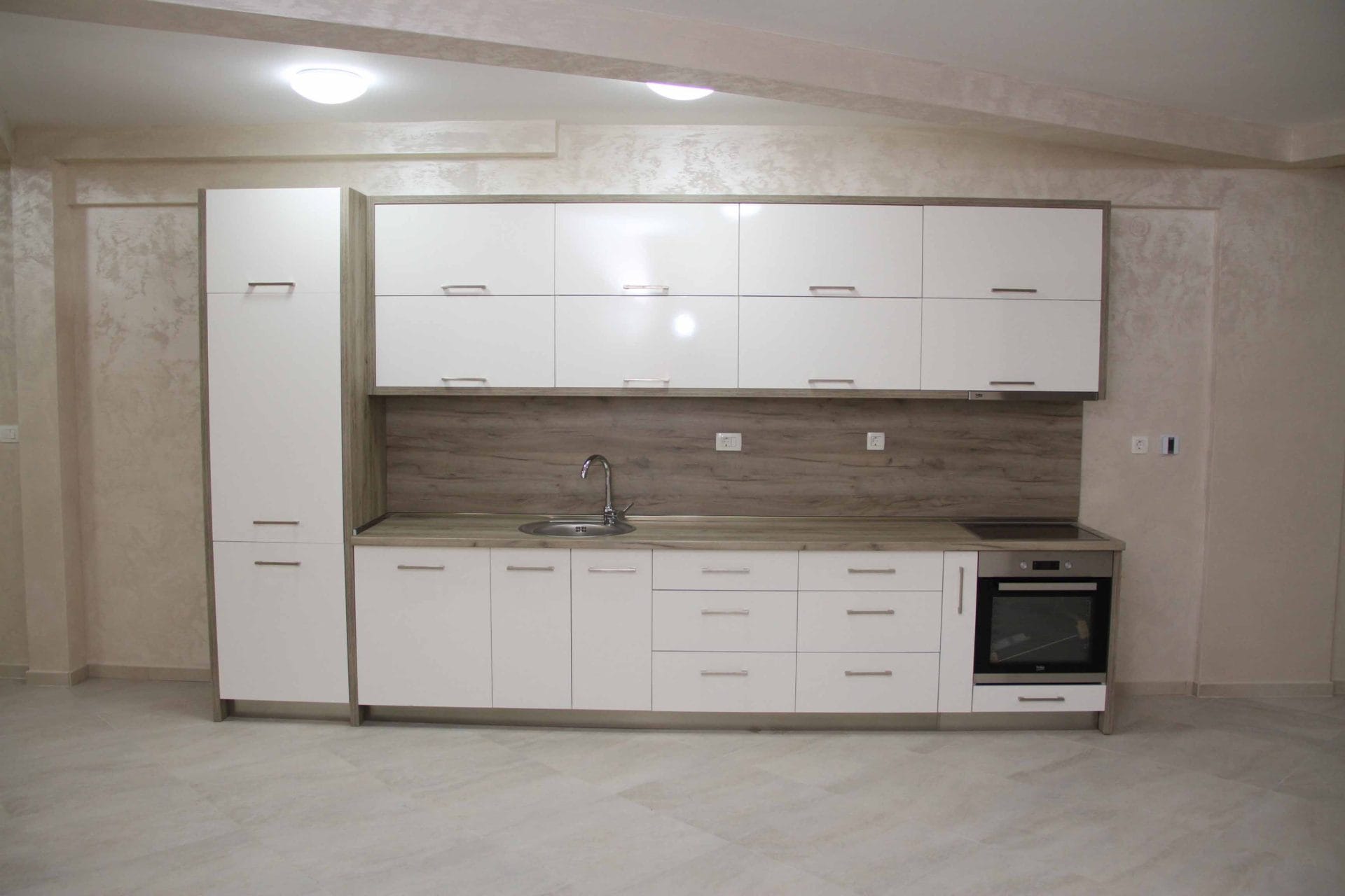 Modern white kitchen with a wooden countertop in an apartment in Petrovac, Montenegro. Built-in appliances and cabinets.