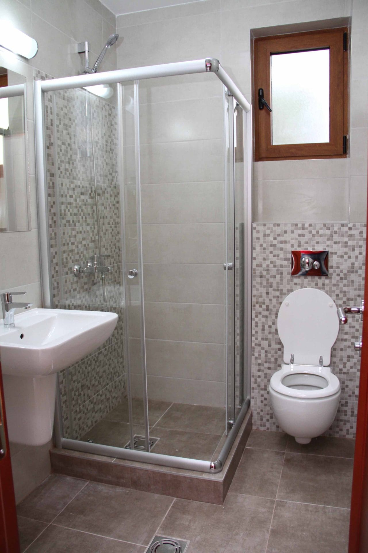 Modern bathroom with a shower cabin and mosaic finishes in an apartment in Petrovac, Montenegro.