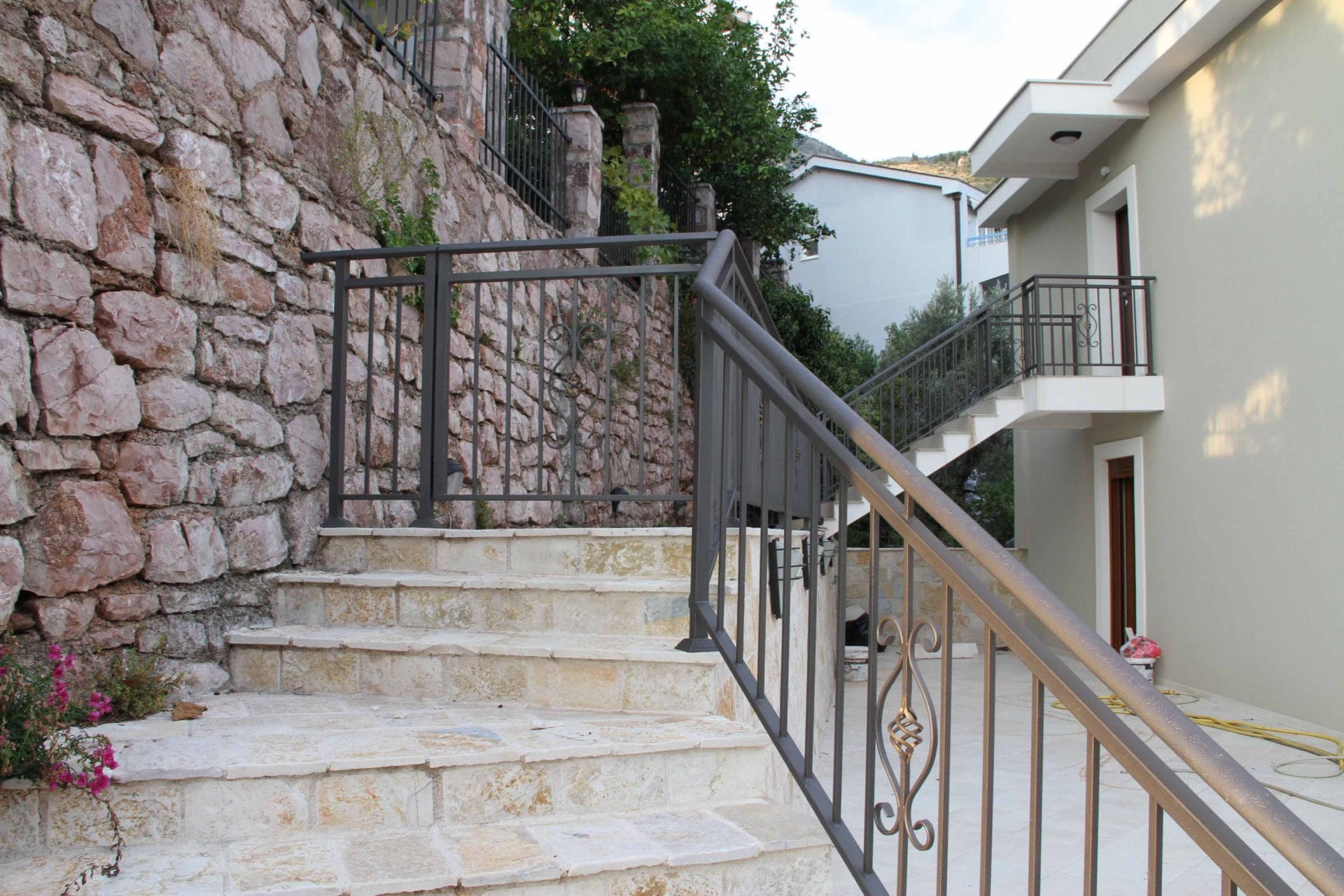 Stone staircase with wrought-iron railings by a house in Petrovac, Montenegro: entrance area and facade finish.