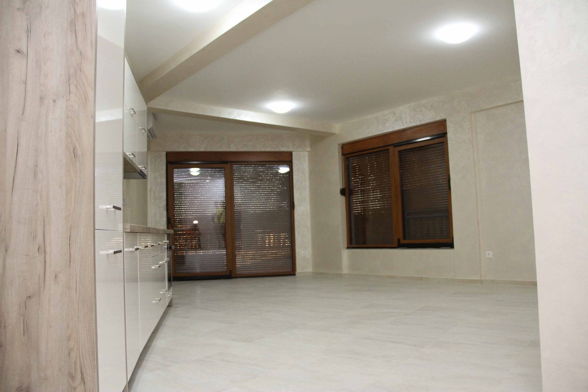 Modern kitchen in an apartment in Petrovac, Montenegro: bright interior, glossy fronts, and panoramic windows with roller shutters.