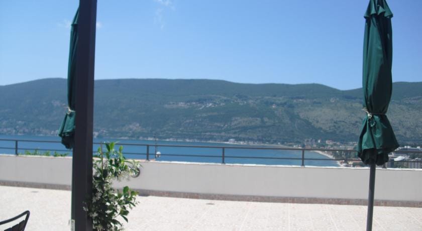 Herceg Novi, Karadağ’daki evde deniz ve dağ manzaralı geniş teras, güneş şemsiyeleri ve korkuluklu.