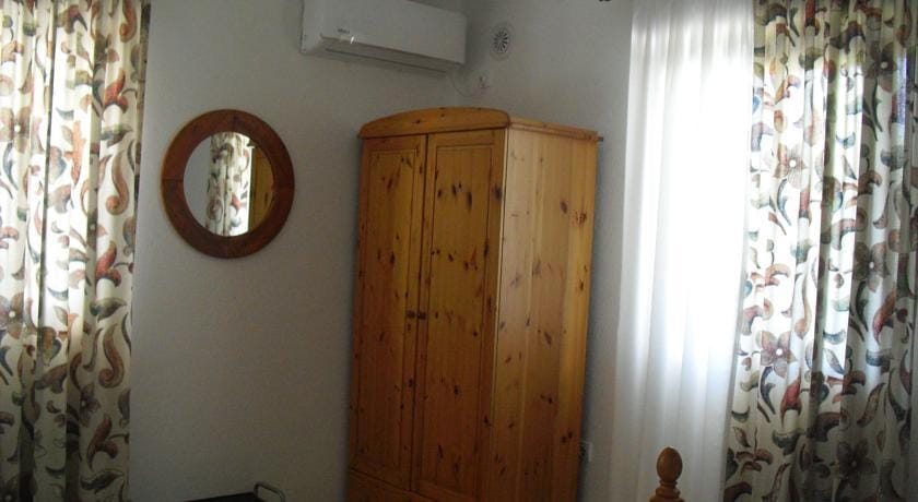 Karadağ, Herceg Novi’deki evde yatak odası: ahşap gardırop, yuvarlak ayna, klima ve çiçek desenli perdeler.