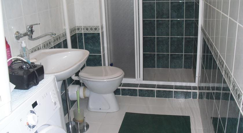 Hersek Novi, Karadağ’daki evde duş kabini ve çamaşır makinesi bulunan banyo. Duvarlarda fayans kaplama.