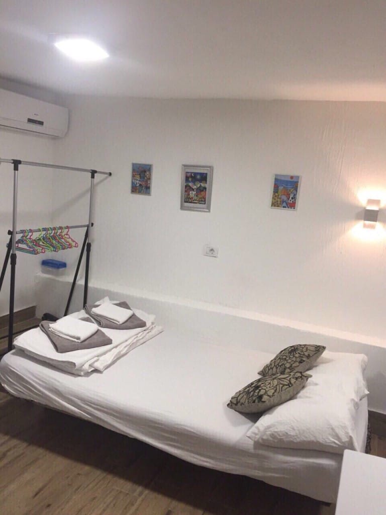 Spavaća soba u mini-hotelu Rafailovići, Crna Gora: svetla soba sa krevetom, klima-uređajem i podnim vešalicom.