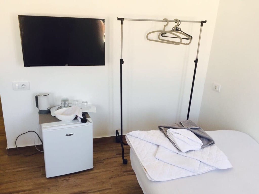 Enterijer spavaće sobe u hotelu Rafailovići, Crna Gora: krevet, TV, mini frižider, kuvalo i podni stalak za odeću.