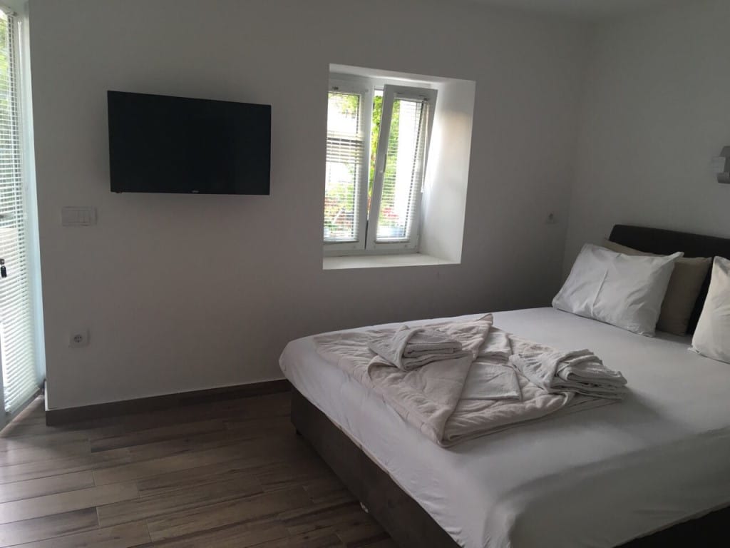 Spavaća soba u mini-hotelu Rafailovići, Crna Gora: bračni krevet, TV na zidu i svetao enterijer.