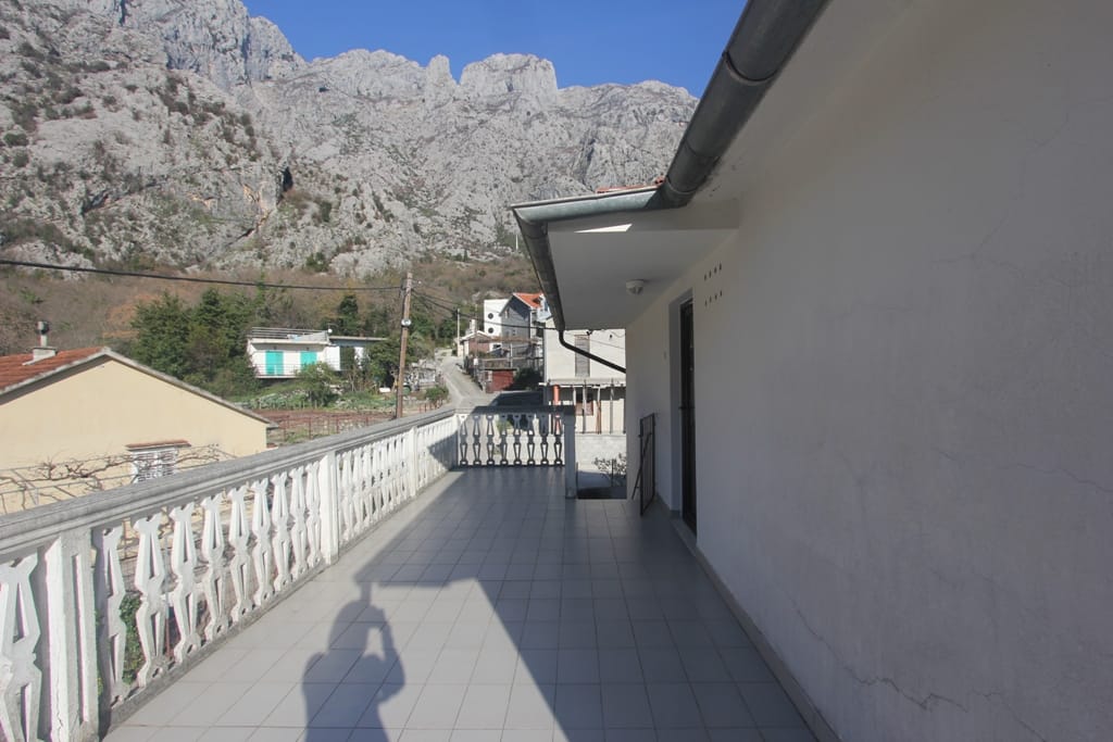 Geräumiger Balkon mit Balustrade und Bergblick in einem Haus, Orahovac, Montenegro. Fliesenboden, helle Fassadengestaltung.