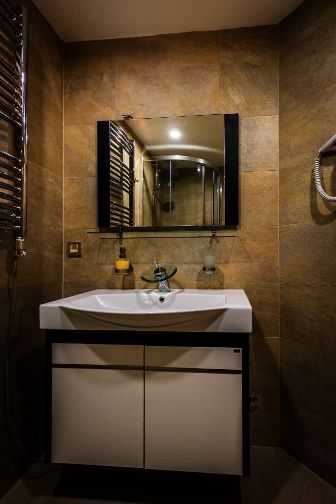 Krašići, Karadağ’daki villada beyaz dolap ve aynalı modern banyo: duvarlar kahverengi fayansla kaplı.