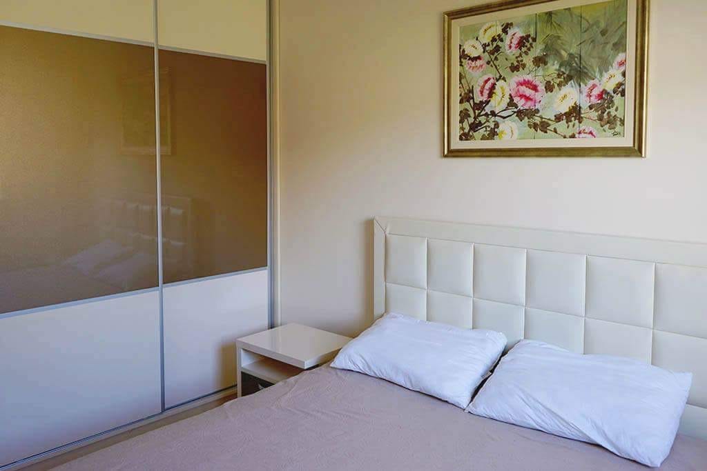 Gemütliches Schlafzimmer in einer Wohnung in Budva, Montenegro: Doppelbett mit gepolstertem Kopfteil und Einbauschrank im Interieur.