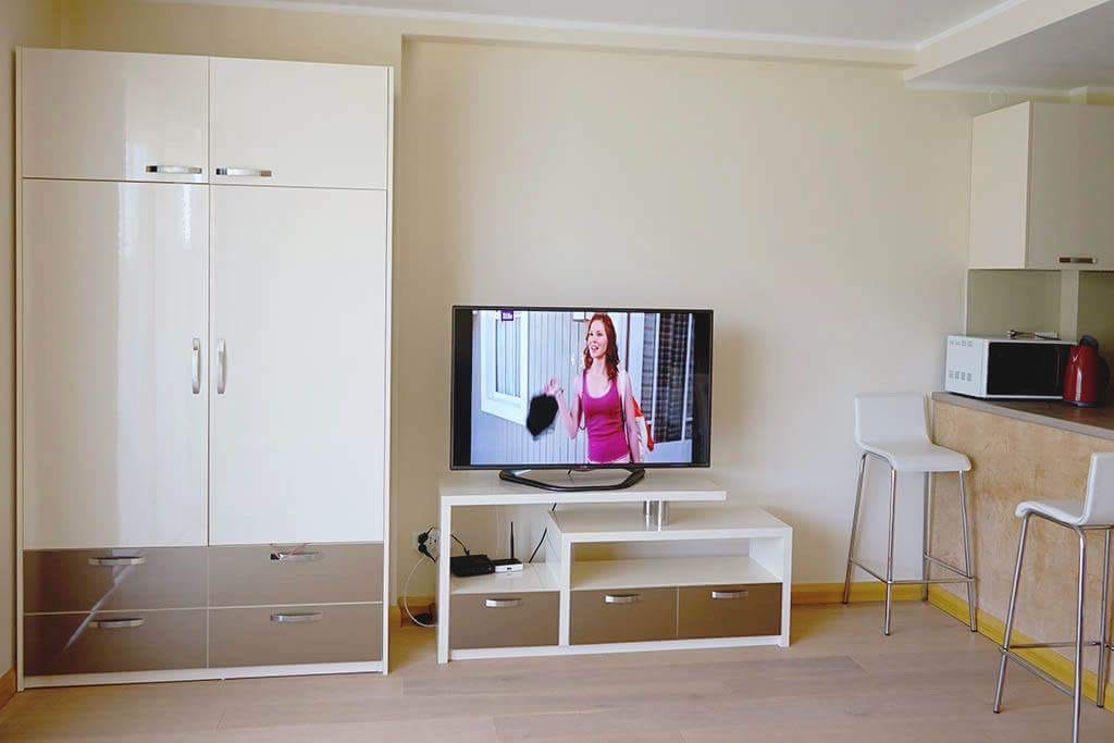 Wohnzimmer in einer Wohnung in Budva, Montenegro: weißer Schrank, TV-Lowboard, Bartheke und moderne Innenausstattung.