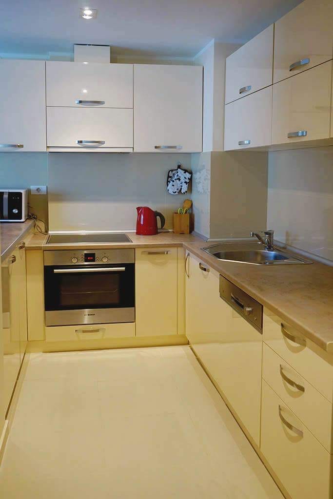 Moderne helle Küche in einer Wohnung in Budva, Montenegro: glänzende Fronten, eingebaute Bosch-Geräte und Spüle.