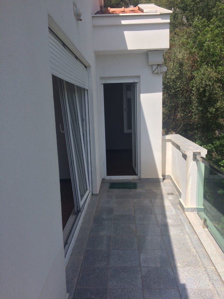 Prostran balkon sa kamenim podom i staklenom ogradom u stanu u Petrovcu, Crna Gora.
