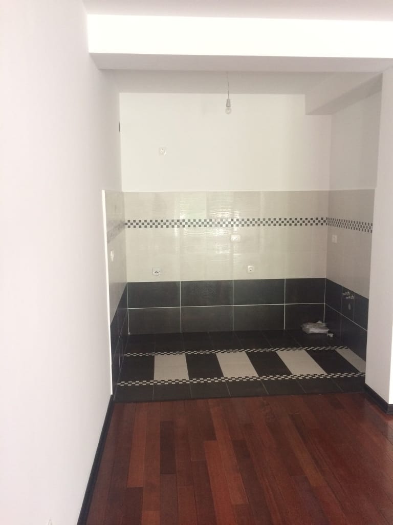 Zona kuhinje u stanu u Petrovcu, Crna Gora: obloga pločicama, tamni pod i parket, priprema za ugradnju nameštaja.