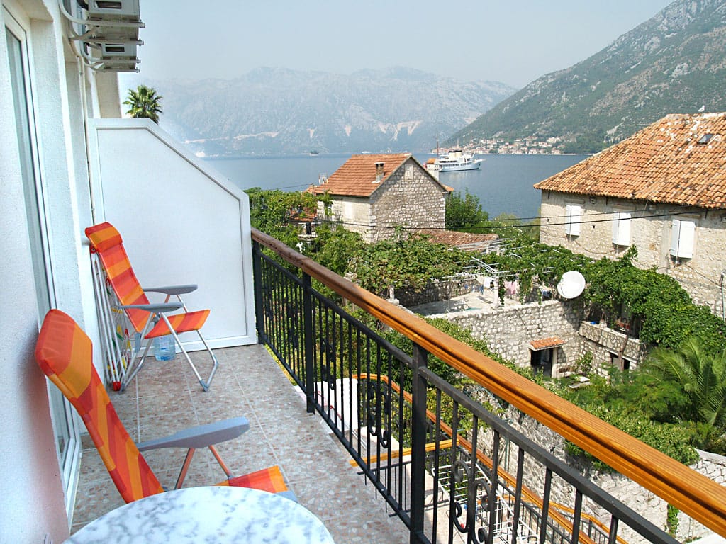 Balkon vile u Stolivu, Crna Gora: pogled na Bokokotorski zaliv, planine i stare kamene kuće sa krovovima od crepa.