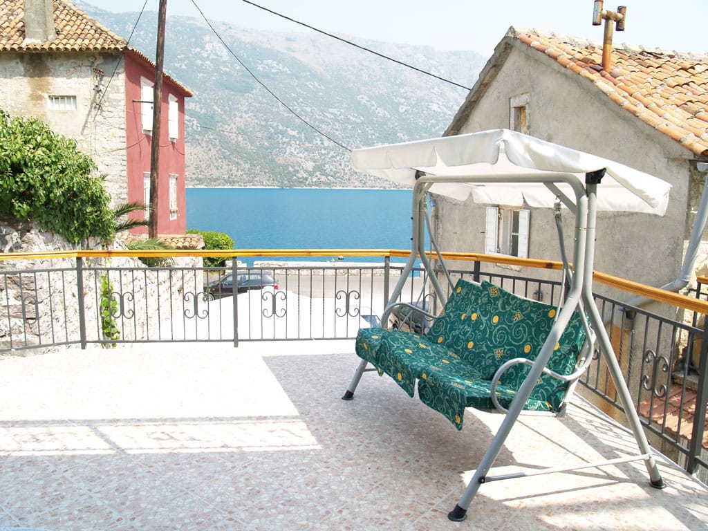 Terasa vile u Stolivu, Crna Gora: baštenska ljuljaška, popločan pod i panoramski pogled na more i planine Bokokotorskog zaliva.