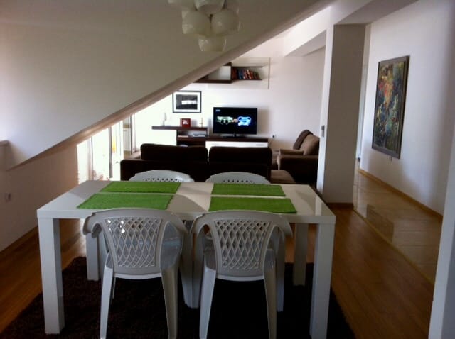 Wohnzimmer in einer Dachgeschosswohnung in Đenovići, Montenegro: Essbereich, weiches Sofa, TV und modernes Interieur.