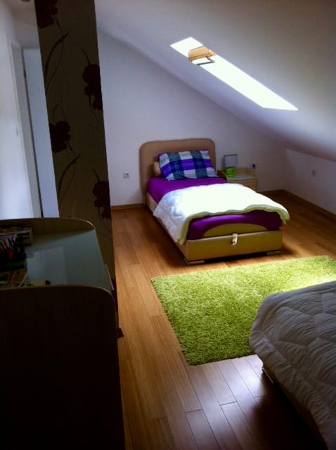 Gemütliches Schlafzimmer im Dachgeschoss einer Wohnung, Đenovići, Montenegro: Bett, Parkettboden und Dachfenster.
