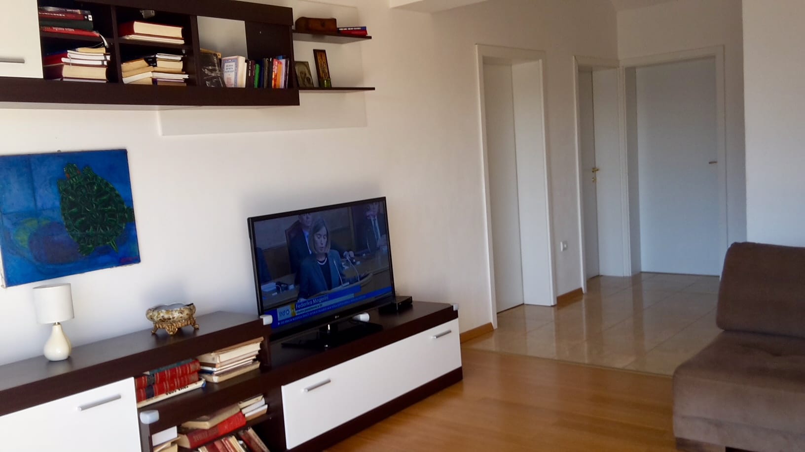Gemütliches Wohnzimmer mit Möbeln, TV und Regalen in einer Wohnung, Đenovići, Montenegro. Helles Interieur mit Holzboden.