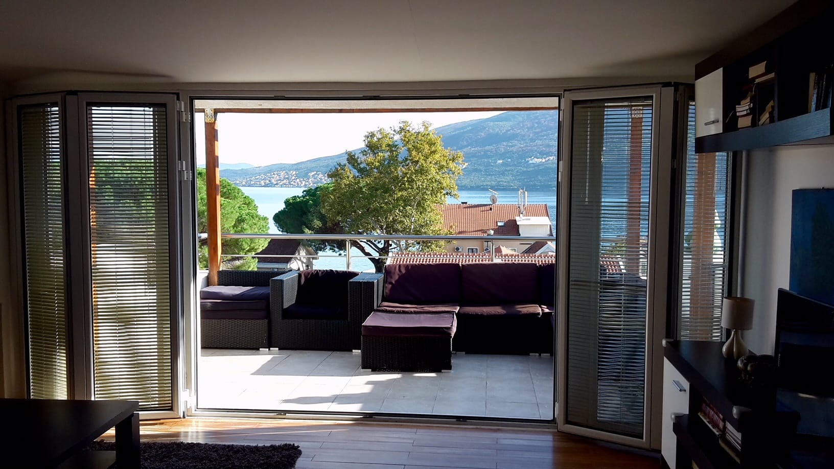 Wohnzimmer mit Zugang zur Terrasse und Meerblick in einer Wohnung, Đenovići, Montenegro: Rattanmöbel, Panoramafenster.
