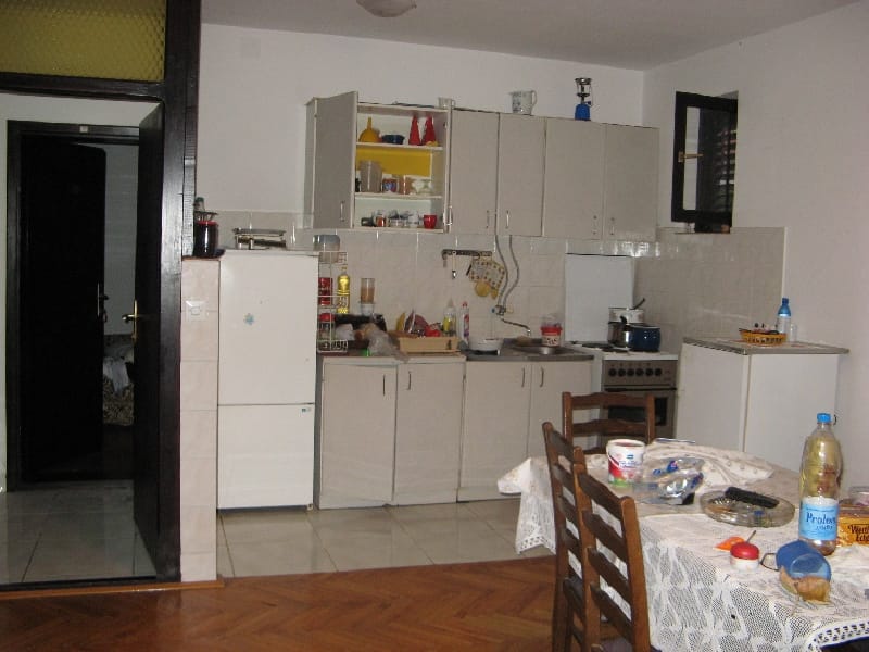 Kitchen in a house in Shushan, Montenegro: light-colored cabinetry, dining table, appliances, and parquet flooring in the interior.