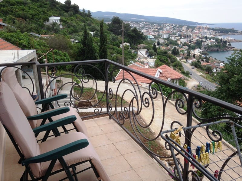 Balkon sa kovanom ogradom i pogledom na more i grad Dobri Vodi, Crna Gora. Postavljene su fotelje za odmor.