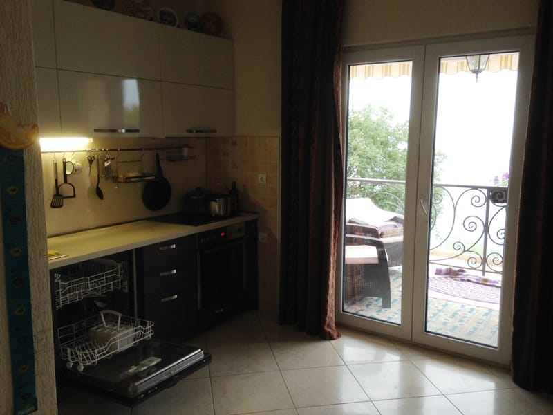 Kuhinja sa modernim nameštajem i izlazom na balkon u kući, grad Dobri Vodi, Crna Gora.