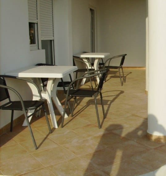 Spacious terrace with plastic furniture in a house in Shushan, Montenegro: tiled floor and light-colored facade finish.