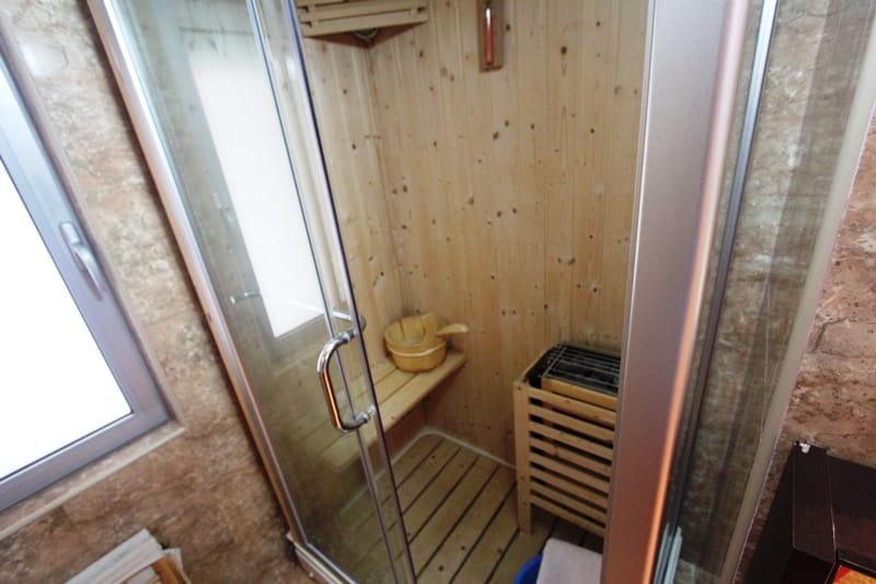 Kompaktna kućna sauna sa drvenom oblogom i peći na kamenje u kupatilu stana u Budvi, Crna Gora.