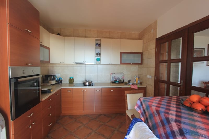 Kitchen in a house in Shushan, Montenegro: wooden cabinetry, built-in appliances, dining table, and tiled floor.