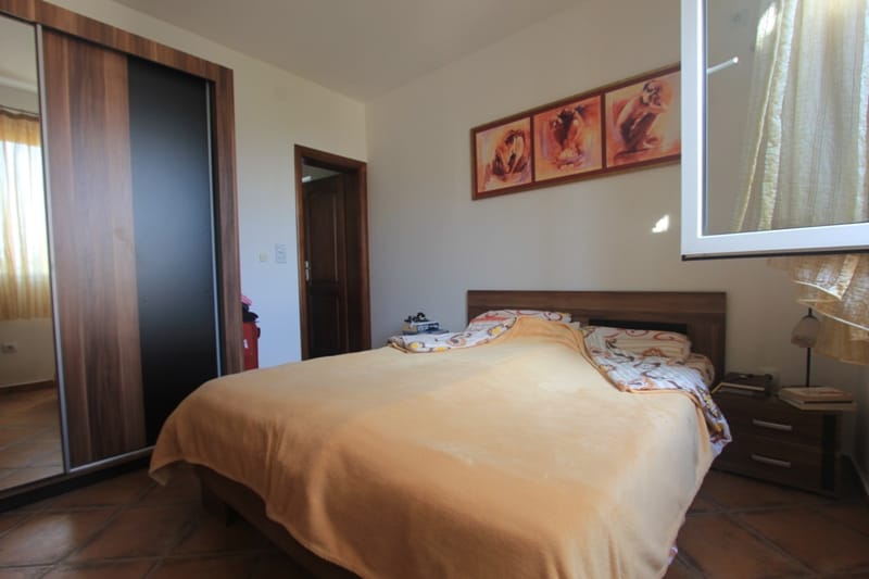 Bedroom in a house in Shushan, Montenegro: double bed, built-in wardrobe, tiled floor, and a painting above the headboard.
