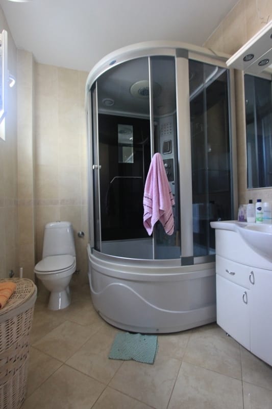 Bathroom in a house in Shushan, Montenegro: a hydromassage shower cabin, white sanitary ware, and light-colored tiles.