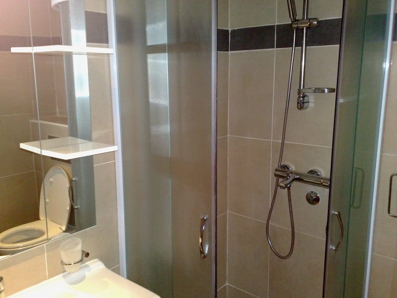 Modernes Badezimmer mit Duschkabine und hellen Fliesen in einer Wohnung zum Verkauf in Pržno, Montenegro.