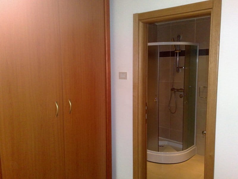 Einbauschranks aus Holz und Eingang zum Badezimmer mit Duschkabine in der Wohnung, Pržno, Montenegro.