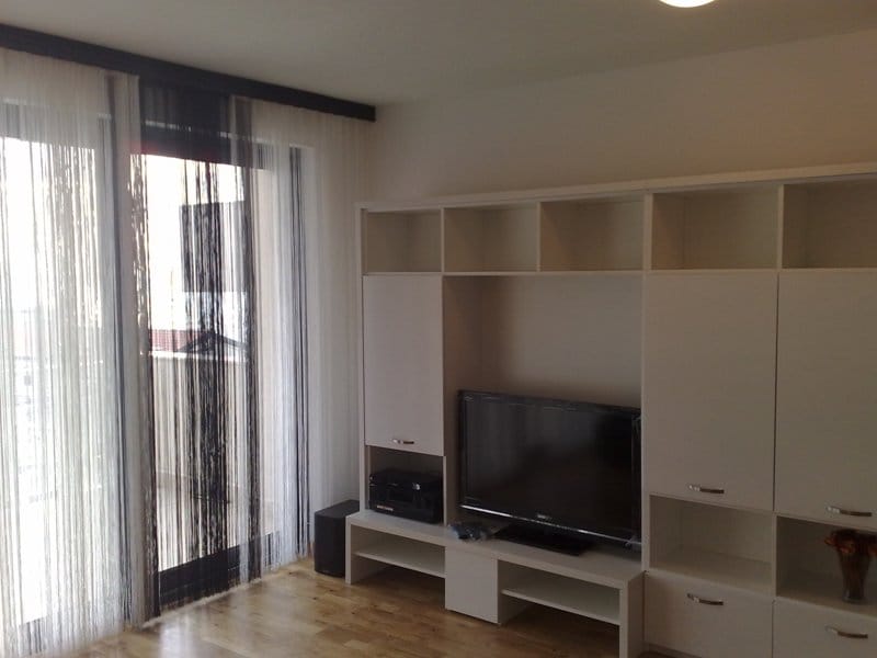 Wohnzimmer mit weißen Möbeln und Zugang zum Balkon in einer Wohnung in Pržno, Montenegro. Modernes Interieur mit TV-Bereich.