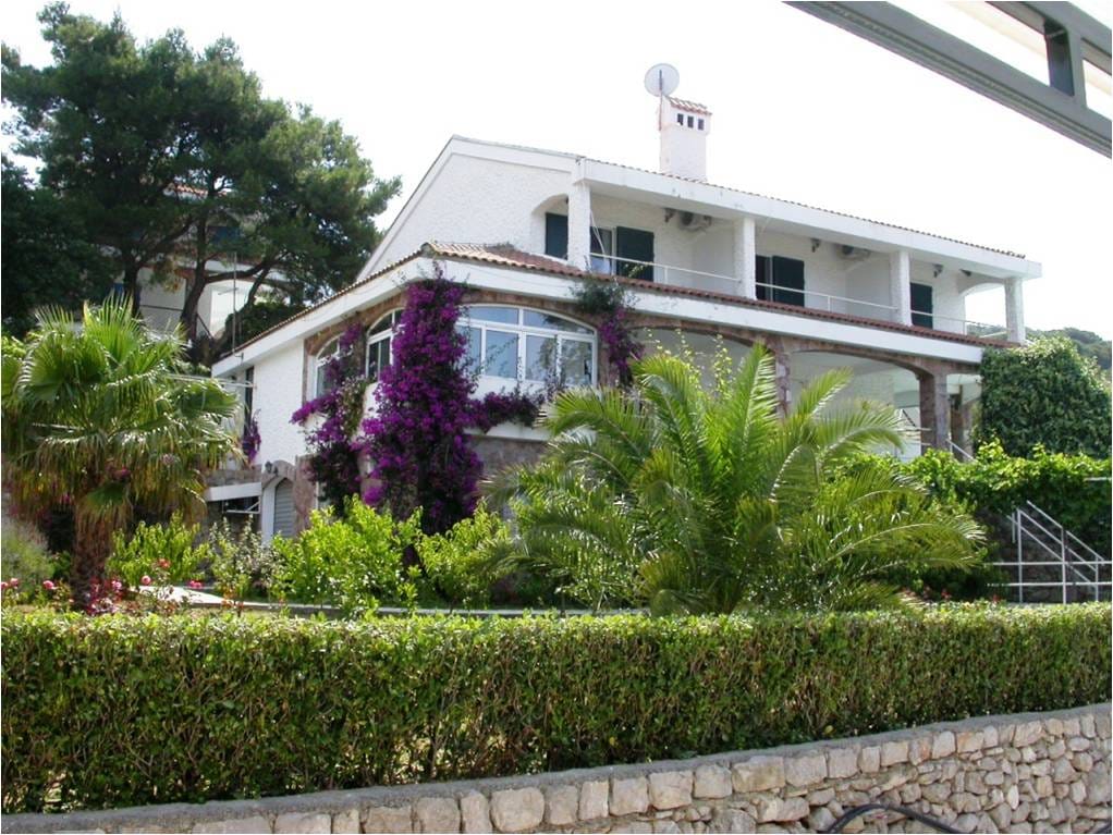 Bela vila sa terasama i cvetajućim bugenvilijama okružena palmama, kuća u Luštici, Crna Gora, spoljašnji pogled.