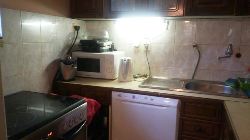 Cuisine dans une maison à Dobrota, Monténégro : armoires en bois, cuisinière, lave-vaisselle et appareils électroménagers sur le plan de travail.