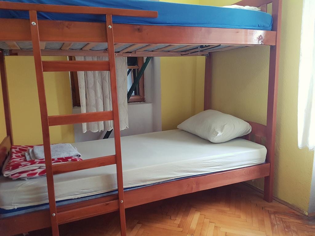 Lit superposé en bois dans la chambre d’une maison à Dobrota, Monténégro, avec parquet et murs jaunes.