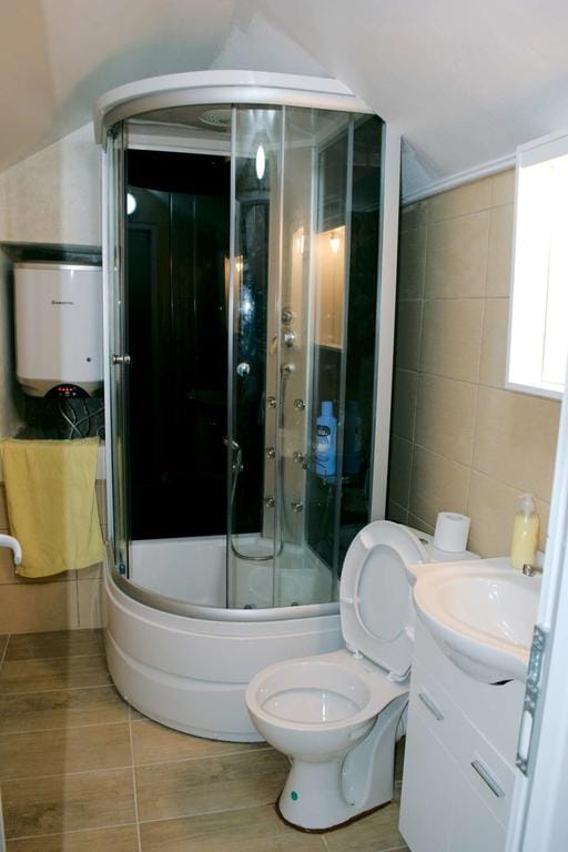 Salle de bains avec cabine de douche et chauffe-eau dans une maison, ville de Dobrota, Monténégro. Sanitaires et carrelage modernes.