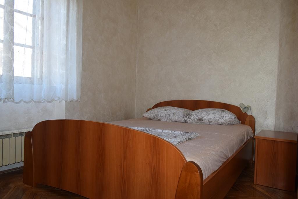 Chambre avec lit double et table de chevet dans une maison, ville de Dobrota, Monténégro. Finition murale claire.