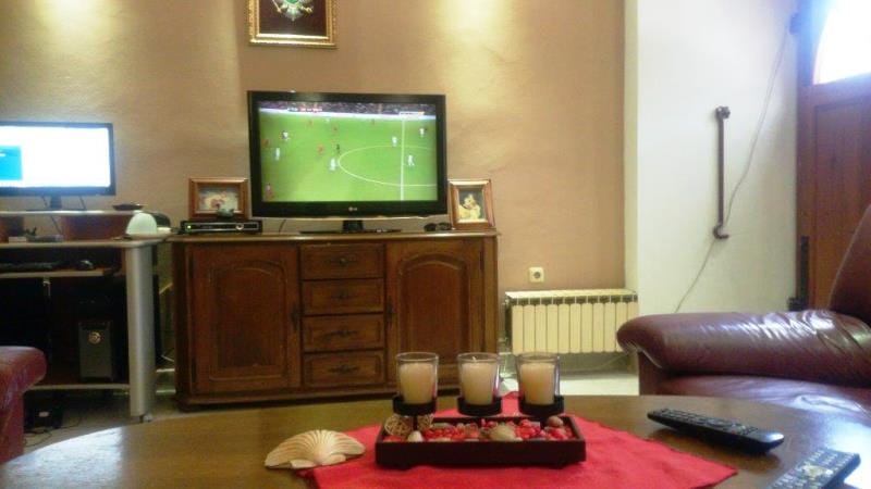 Salon confortable dans une maison à Dobrota, Monténégro : meuble TV en bois, mobilier en cuir et table basse avec des bougies.