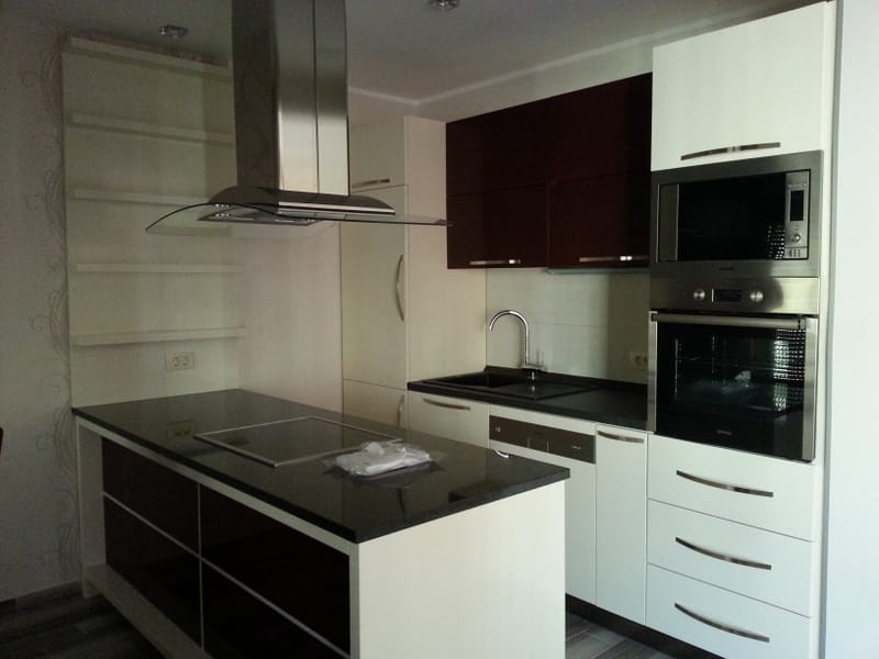 Moderne Küche mit Insel und Einbaugeräten in einer Wohnung in Bečići, Montenegro. Stilvolles Interieur mit Möbeln.