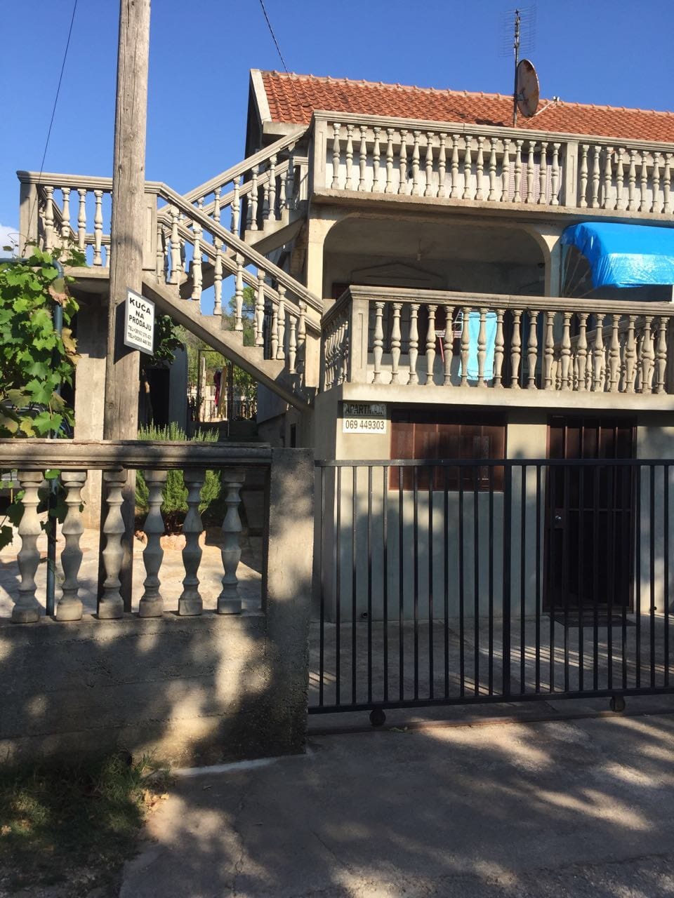 Dvospratna kuća na prodaju u Krimovici, Crna Gora: fasada sa betonskim balustradama, spoljnim stepeništem i kapijom.