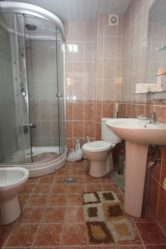 Kupatilo u stanu u Bečićima, Crna Gora: tuš kabina, sanitarije, obloga od pločica u bež tonovima.