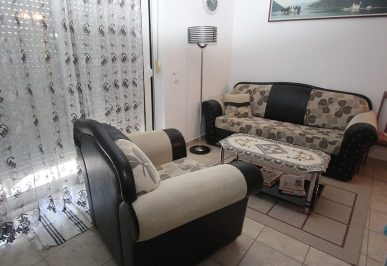 Ugodan dnevni boravak u stanu u Bečićima, Crna Gora: udoban kutak sa sofom, foteljom, klub stolom i podnom lampom.