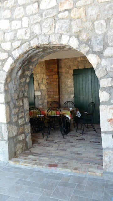 Villa terrace in Shushan, Montenegro: stone arch, wrought-iron furniture, and brick detailing in Mediterranean style.