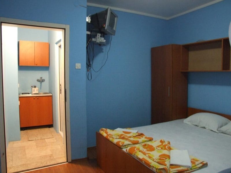 Spavaća soba sa bračnim krevetom i kuhinjskim delom u kući, grad Bečići, Crna Gora. Budžetski enterijer sa nameštajem.